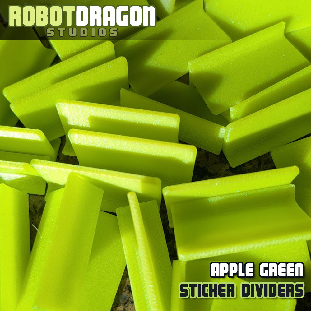 Close up photo of a messy pile of 3D printed apple green iridescent PETG sticker dividers designed and created by Robot Dragon Studios for artist alley.