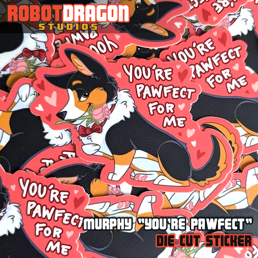 Close-up of a pile of die-cut stickers featuring a dashing tricolor corgi named Murphy, wearing a red bow tie and holding a pink rose in his mouth. The sticker has a pink heart-filled background and the text ‘You’re Pawfect For Me,’ creating a Valentine’s Day theme.