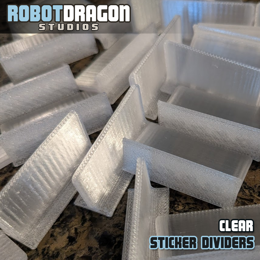 Close up photo of a messy pile of 3D printed clear translucent PETG sticker dividers designed and created by Robot Dragon Studios for artist alley.
