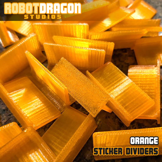 Close up photo of a messy pile of 3D printed orange translucent PETG sticker dividers designed and created by Robot Dragon Studios for artist alley.