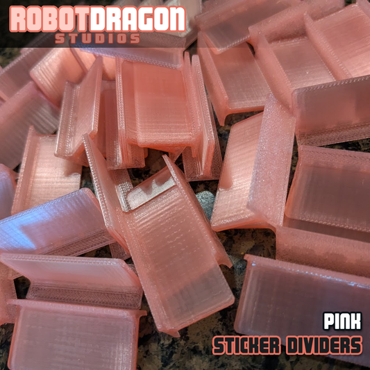 Close up photo of a messy pile of 3D printed pink translucent PETG sticker dividers designed and created by Robot Dragon Studios for artist alley.